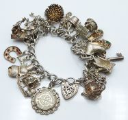 A silver charm bracelet with over 20 silver charms, 83g