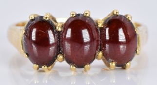 An 18ct gold ring set with three garnet cabochons, 3.6g, size M