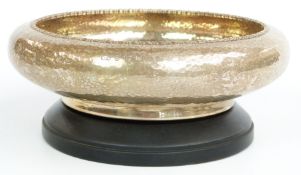 George V hallmarked silver bowl with Arts & Crafts style hammered finish, on ebonised stand,