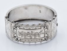 A hallmarked silver Victorian bangle bracelet with engraved floral decoration and jewelled edge (
