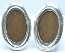 Pair of George V oval hallmarked silver photograph frames with oak easel backs, Birmingham 1924/5,
