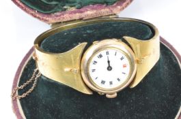 Edwardian 9ct gold watch set into a yellow metal bangle, in original box. 22.6g (Bangle sizing-