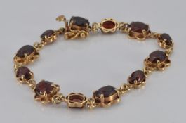 A 9ct gold bracelet set with oval cut garnets, 11.9g
