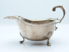 Victorian hallmarked silver gravy boat with scrolling handles and raised on three hoof feet, Chester