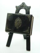 A late 19th/20thC sewing / needlework box in the form of a leather book with brass clasp, on an