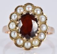 A 9ct gold ring set with an oval garnet surrounded by pearls, 3.8g, size L