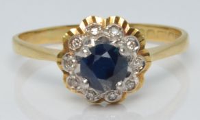 An 18ct gold ring set with a round cut sapphire surrounded by diamonds, 2.8g, size O