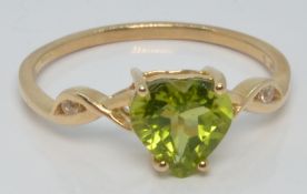 A 10k gold ring set with a heart cut peridot and white zircon, with certificate, size U