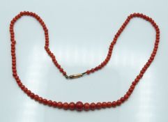 A beaded coral necklace with yellow metal clasp