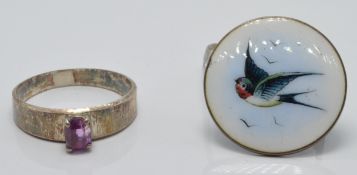 A silver brooch set with enamel depicting a swallow and a silver ring set with a pink sapphire