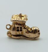 A 9ct gold boot charm opening to reveal four figures, 2.7g