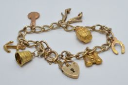 A 9ct gold charm bracelet with seven 9ct gold charms including horse shoe, barrel, binoculars etc,