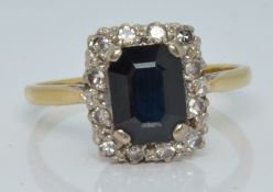 An 18ct gold ring set with an emerald cut sapphire and diamonds, 3.4g, size P