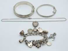 Two silver bangles one by Charles Horner, charm bracelet and a locket, 110g