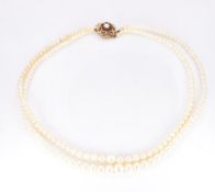 A two strand cultured pearl necklace, the 9ct gold clasp set with garnets and a pearl