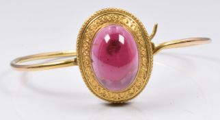 Victorian Etruscan Revival bangle set with a garnet cabochon and sphere and detailed border, 11.