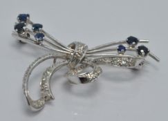 A platinum brooch set with sapphires and diamonds in a stylised bow design, 4 x 2.5cm
