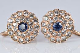A pair of yellow metal earrings set with a blue and white sapphires in a cluster