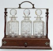 Edwardian oak three-bottle tantalus, with Bramah or similar lock, height 32cm