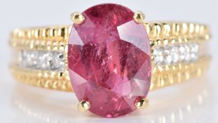 An 18ct gold ring set with an oval cut ruby and diamonds, 7.7g, size N