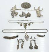 Two Siam silver brooches depicting deities, a silver pendant depicting a mask, white metal knife