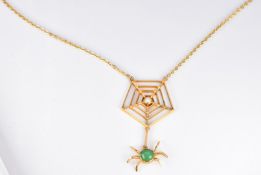 A yellow metal pendant in the form of a spider and web set with a jadeite cabochon and a seed pearl,