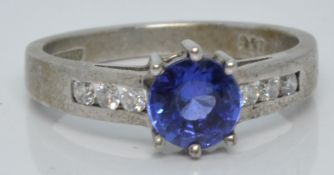 An 18ct white gold ring set with a round cut tanzanite and diamonds to the shoulders, with