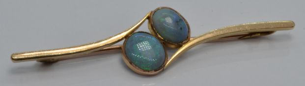 An early 20thC yellow metal brooch set with two oval opal cabochons, in vintage box, 6cm