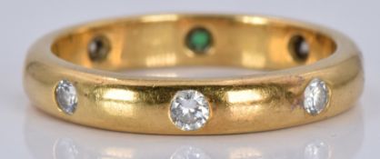 An 18ct gold eternity ring set with an emerald and diamonds, 4.4g, size M