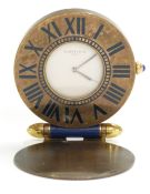Cartier brass folding travelling clock, the white dial with inlaid blue enamel Roman numerals and