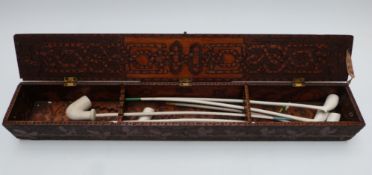 A 19thC pokerwork decorated clay pipe box with long clay pipes within, the box W66 x D9.5 x H10cm,