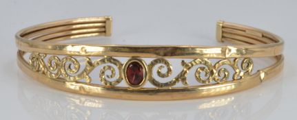 A 9ct gold bangle set with a garnet, 6.4g