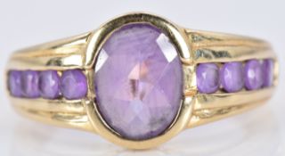 A 9ct gold ring set with an oval cut amethyst and four further round cut amethysts to each shoulder,
