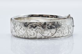 A hallmarked silver bangle with engraved scrolling decoration, 50g