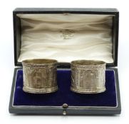 A cased pair of Victorian hallmarked silver napkin rings decorated with classical scenes in relief