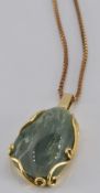 An 18ct gold pendant set with jade (5.1g) on a 9ct gold chain (4.0g)