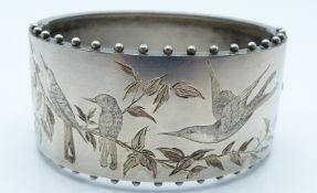 Victorian white metal bangle with engraved decoration depicting birds amongst foliage, stamped