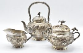 Chinese white metal three piece teaset with embossed iris decoration and flower handles, marked to