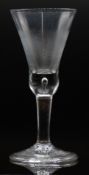 An 18thC wine or ale glass with folded foot, control bubble decoration and thistle shaped bowl, 22cm
