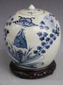 A 19thC covered ginger jar decorated with moths amongst foliage, raised on a carved hardwood