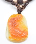 Two Chinese orange jade pendants, one depicting a creature (5.5 x 3.8cm) and the other peaches, 4.