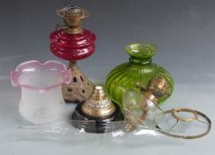 Two brass oil lamps including one with red glass globe and a further green lobed glass shade.