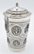 Indian white metal lidded beaker with embossed deity decoration, 13cm tall, weight 147g