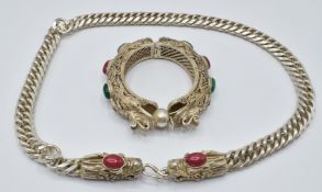 A white metal necklace with dragon head clasp and a bangle depicting two dragons chasing a flaming