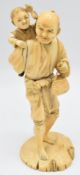 A 19thC Japanese Meiji period signed ivory okimono of a smiling man with child on his back, with