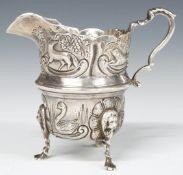 Edward VII hallmarked silver jug with embossed decoration, raised on three feet, Birmingham 1904,