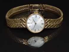 Omega 9ct gold ladies wristwatch with black hands, black and gold baton hour markers, silver dial