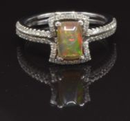 An 18ct white gold ring set with an Australian opal surrounded by diamonds and with further diamonds
