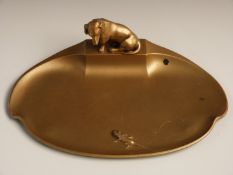 Gilded dish with figural decoration of a Dachshund staring at a lizard, width 23cm