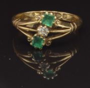An 18ct gold ring set with a round cut diamond and two square cut emeralds, Chester 1915, size M,